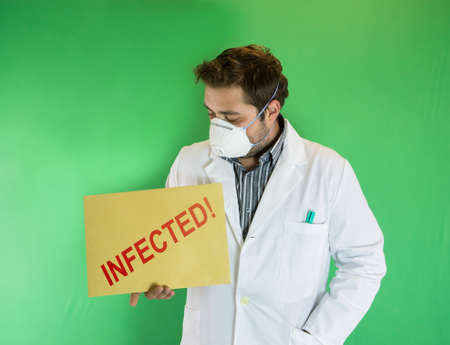 Young doctor with face mask holding sign with infected text.の写真素材