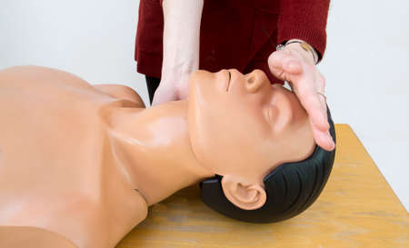 Young woman making head hyperextension during CPR maneuvers on a dummy, learning how to act in case of cardiopulmonary arrest.の写真素材