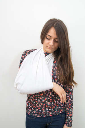 A young woman with her arm immobilized. Learning first aid in case of broken arm.の写真素材