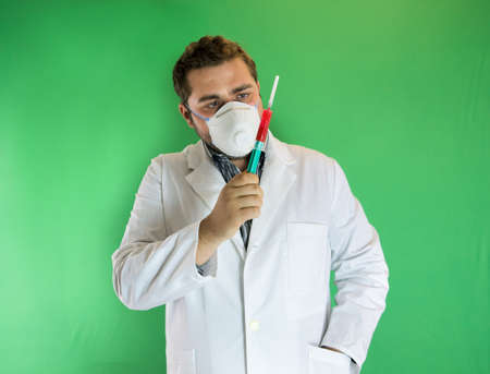 Young doctor with mask analising a syringe with blood sample.の写真素材
