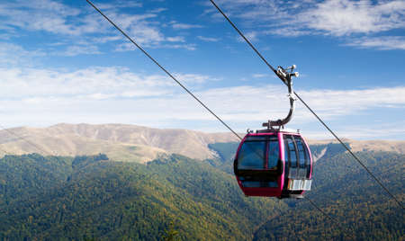 Cable car going downhill with mountain landscape in the background.の写真素材