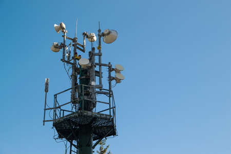 Communication tower with multiple antennas and blue sky in backgroundの写真素材