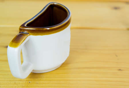 Half of a coffee mug. White cup with brown edge on wooden texture table. Space available for text. (Copy space available)の写真素材