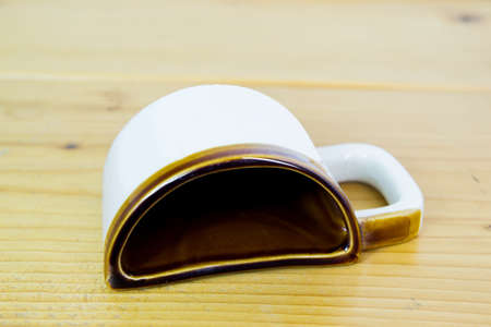 Half of a coffee mug. White cup with brown edge on wooden texture tableの写真素材
