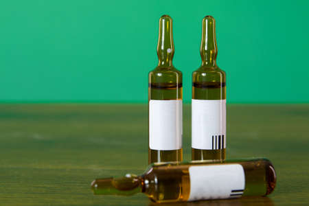 Vial of drug or vitamins on wood table and medical green background.の写真素材