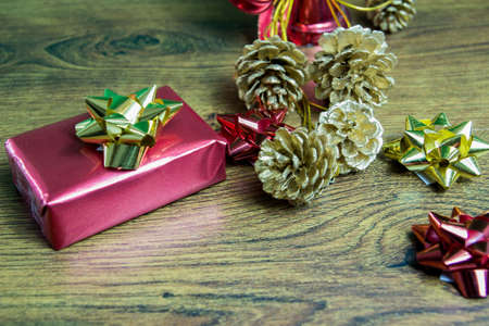 Wrapped gift and Christmas decorations. Golden pine tree cones and shining ribbons.の写真素材