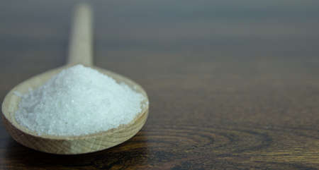 White sugar in a wood spoon on wooden table.の写真素材