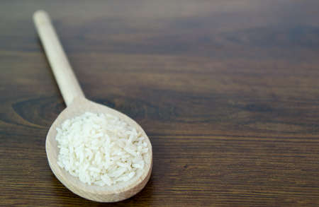 Rice in a wooden spon. Wood texture table.の写真素材