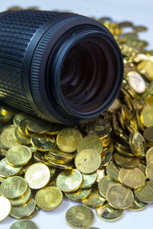 DSLR photo lens on pile of golden coinsの写真素材