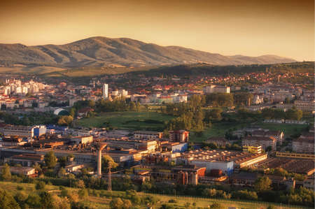 Aerial view of an orange sunset over a small town with a hill or mountain in the background の写真素材