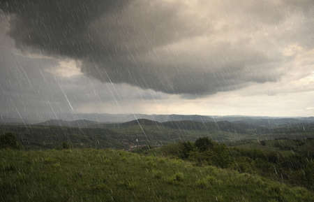 landscape with rain and dramatic clouds over hills の写真素材