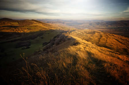 Beautiful autumn landscape with last rays of sun shining on hillの写真素材