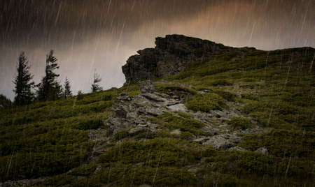 Rain falling over mountain cliffs and trees