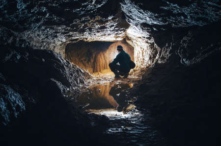 Underground cave with man exploring with lightの写真素材