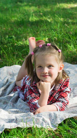 little girl lies on a Mat on the grass and smilingの写真素材