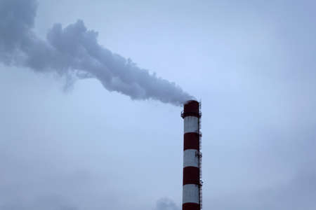 high pipe CHP on the background of blue sky, fog, smog, and out clouds of thick smoke, pipe red-and-white, it's cold outsideの写真素材