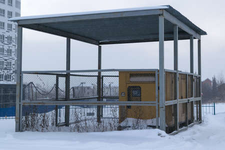 several diesel generators yellow stand under a canopy is fenced with a metal grid, lying on the street white snow, winter, sky, fog, smogの写真素材
