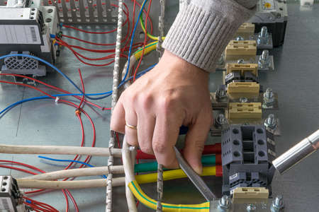 Man with a wrench fastens the nut ground wire with the lug bolted to the entrance terminal.の写真素材