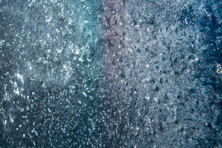 On glass window frost abstract patterns. Shimmer in different colors. White, purple, blue, celadon, pink. Winter, cold. Strong frost.の写真素材