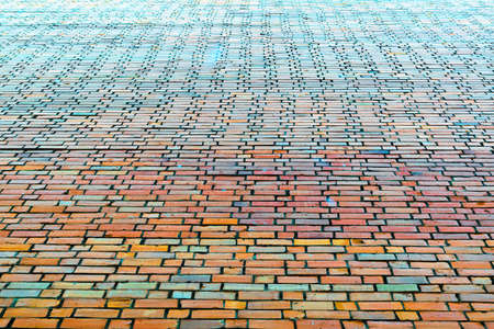 End brick wall of the big house. Bricks of different colors. Red, orange, green, blue. Brick wall gets in the future. The cement joints between rows of bricks bonded structure.の写真素材