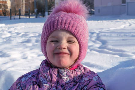 The girl in the Park in winter closed his eyes. White lies the snow. The little girl is wearing a...