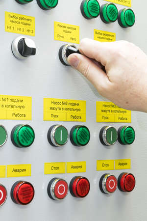 A man holds the hand of the head switch of the electric Cabinet. On the door of the electric Cabinet...
