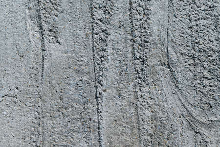 A piece of concrete wall with pebbles and stripes. Recesses in the concrete wall in the form of vertical stripes. In concrete inclusions of small pebbles of gray and brown.の写真素材