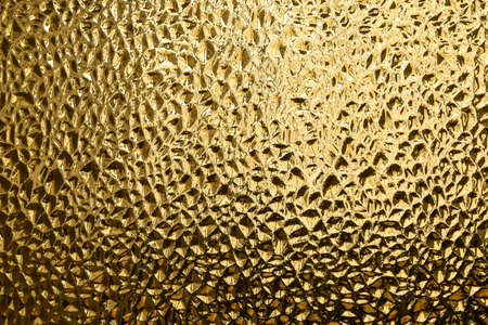 Glass with embossed wave pattern in the form of small pits or depressions. Glass yellow or gold color. Recesses of medium size.の写真素材