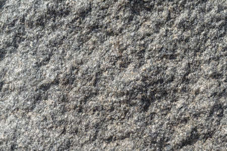The rough surface of a granite piece of stone. Seen small rocks and bumps. Granular surface with pits and tubercles.の写真素材