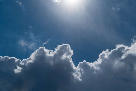 Blue sky with Cumulus clouds. Top the sun shines. The bright sun illuminates Cumulus clouds. The sky is clear and blue. A small haze.の写真素材