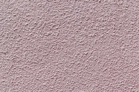 The wall is made of plaster and painted pink or beige paint. Prominent tubercles and pits, or pits. The wall is rough with small cracks.の写真素材