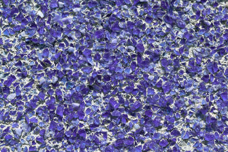 Part of the wall covered with small pieces of purple glass or quartz. Pieces of glass fixed with cement or concrete on the wall. The slides are located in a chaotic manner.の写真素材