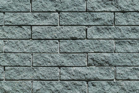 The wall and the bricks are gray or green. Masonry of bricks laid horizontally. The joints between the bricks with cement.の写真素材