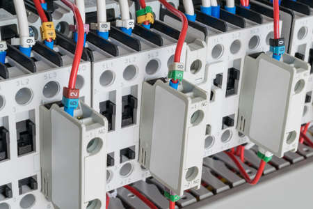 Several contactors arranged in a row in an electrical closet. The contactors connected wire number coded. Contactors with front auxiliary contacts. The wires go into perforated cable channels.の写真素材