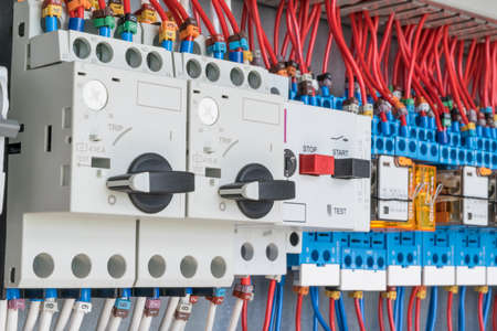 n the electrical control panel are circuit breakers protecting the motor and relay. Circuit breakers with rotary handles and push-button and arranged in a row. Wires with ferrules number coded.の写真素材