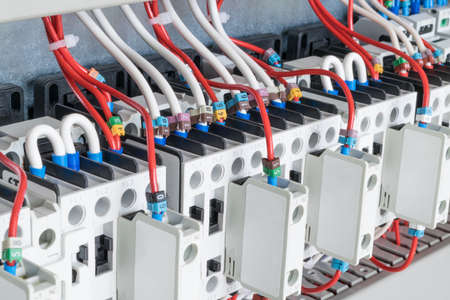 The number of contactors arranged in a row in an electrical closet. The contactors connected wire number coded. Contactors with front auxiliary contacts. The wires go into perforated cable channels.の写真素材