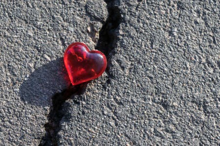 Crack on the pavement. The crack lies heart of glass. The symbol of the rupture of relations. A split or crack in love.の写真素材