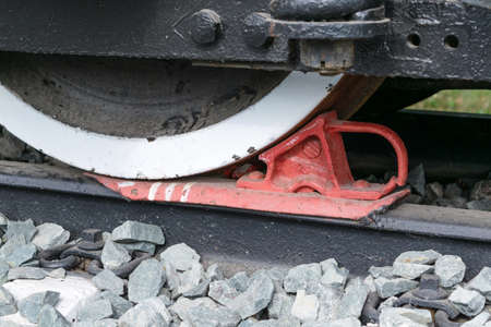 Railway brake Shoe to lock the wheels of railway carriages. Between the rails lies the rubble. Brake painted red paint. Brake Shoe with handle.の写真素材
