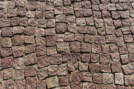 Square lined with cobblestone or stone pavement, walkway or road. The surface of rough stones and rough. Stones brown. Seams of sand. The cobbles have a mottled pattern and texture.の写真素材