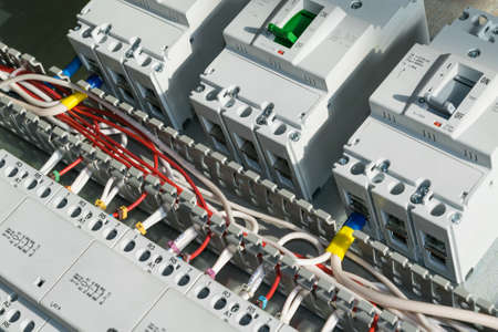 A series of modular magnetic contactors and a range of power circuit breakers. Between the rows of contactors and switches, perforated cable channels. To the contactor of the connected wires.の写真素材