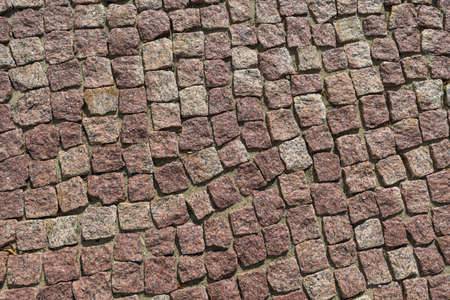 Square lined with cobblestone or stone pavement, walkway or road. The surface of rough stones and rough. Stones brown. Seams of sand. The cobbles have a mottled pattern and texture.の写真素材