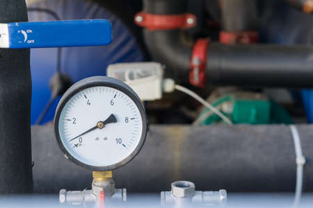 A device for measuring pressure or a pressure gauge on the background of the piping and handle. Design in modular design. The pressure gauge is round with an arrow and numbers.の写真素材
