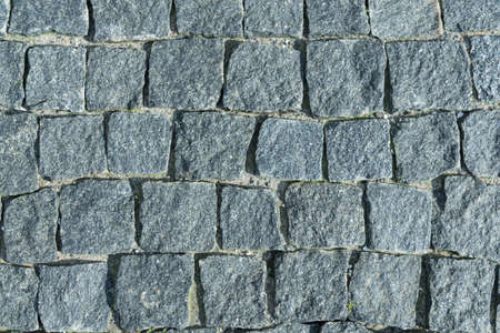 Square lined with cobblestone or stone pavement, walkway or road. The surface of rough stones and rough. Boulders of gray. Seams of small pebbles. The cobbles have a mottled pattern and texture.の写真素材