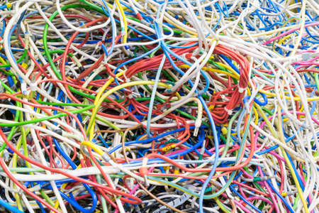 The bunch of electric wires of different colors are very much intertwined. Tangled wire-end ferrules and markings. Wire bound with zip ties. Visible braid. Chaos, confusion, confusion.の写真素材