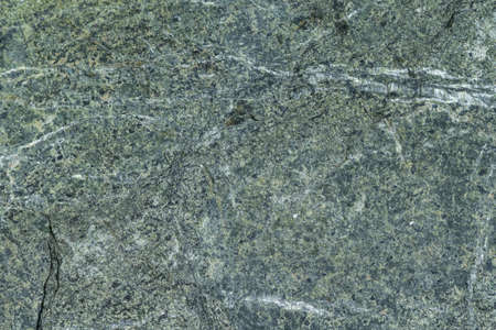 Surface grey granite stone with light lines and streaks. On granite, there are bumps and pits. The structure of granite stone in cross section.の写真素材