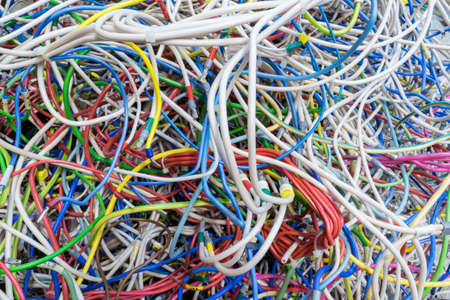 The bunch of electric wires of different colors are very much intertwined. Tangled wire-end ferrules and markings. Wire bound with zip ties. Visible braid. Chaos, confusion, confusion.の写真素材