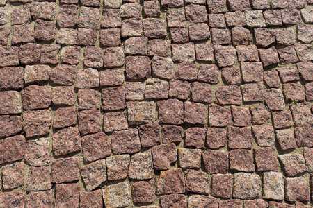 Square lined with cobblestone or stone pavement, walkway or road. The surface of rough stones and rough. Stones brown. Seams of sand. The cobbles have a mottled pattern and texture.の写真素材