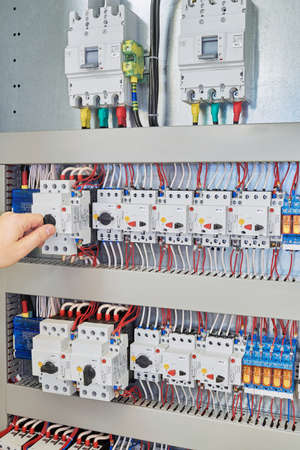 Man switch switch protection engine to check in the electrical Cabinet. In the electrical control Cabinet on a mounting plate fixed circuit-breakers, motor protection relay.の写真素材