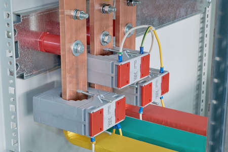 Copper busbars with current transformers on them in an electric Cabinet. Copper busbars are bolted...