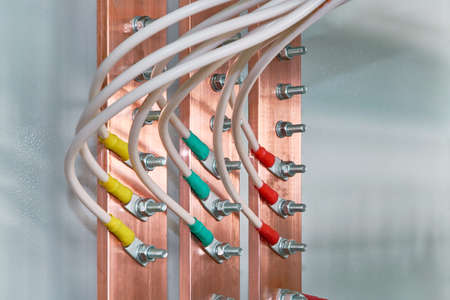 Electric bus bars connected to it by wires or cables. The cables are connected with cable lugs and nuts bolts. Accumulation and interlacing of wires or cables in the electrical Cabinet.の写真素材